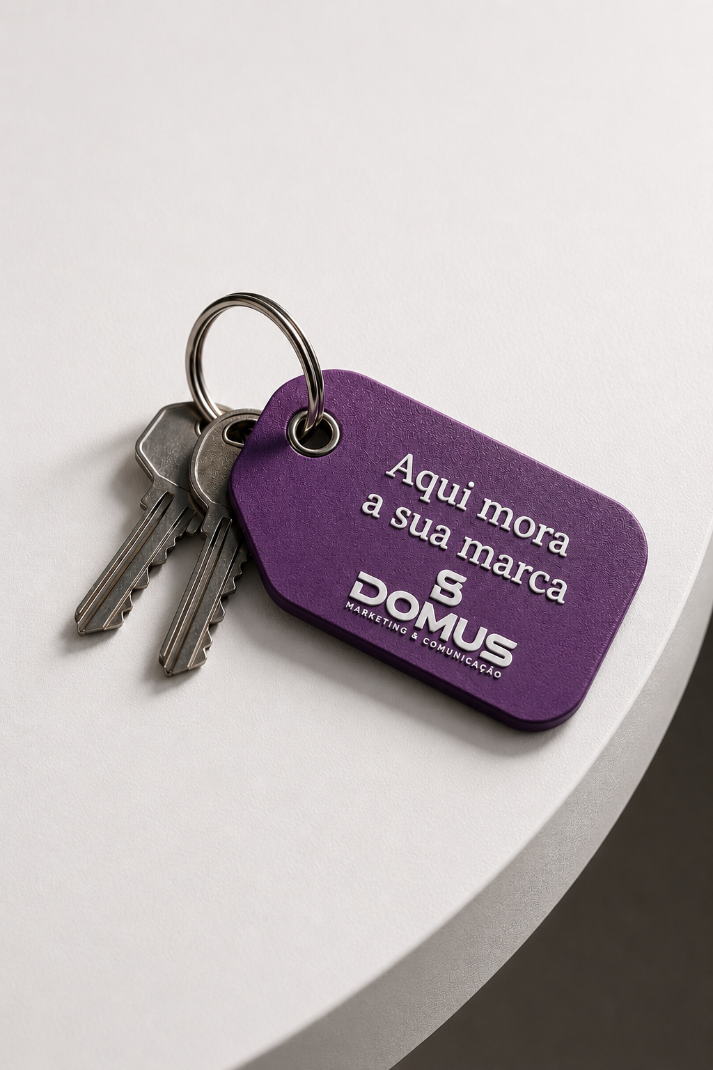 Chaveiro roxo da Domus com a frase 'Aqui mora a sua marca' e duas chaves ao lado